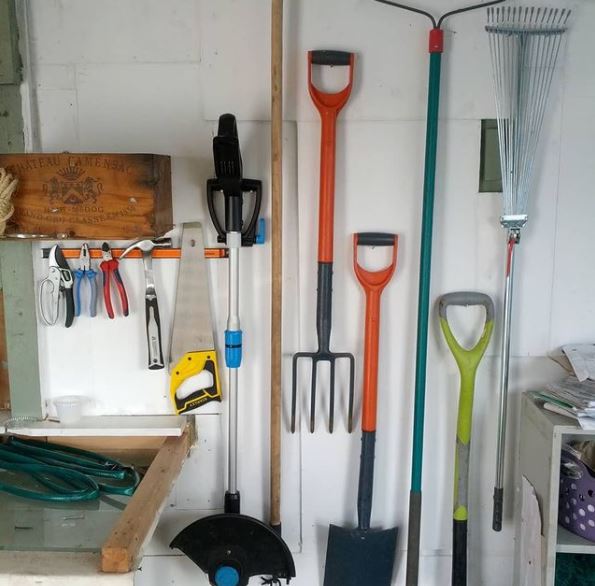 a shed wall with various garden tools hanging on hooks