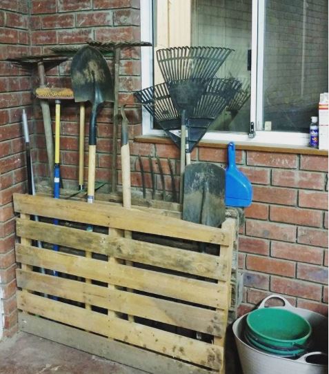 wooden pallets have been turned into storage bins for long garden tools like rakes and brooms